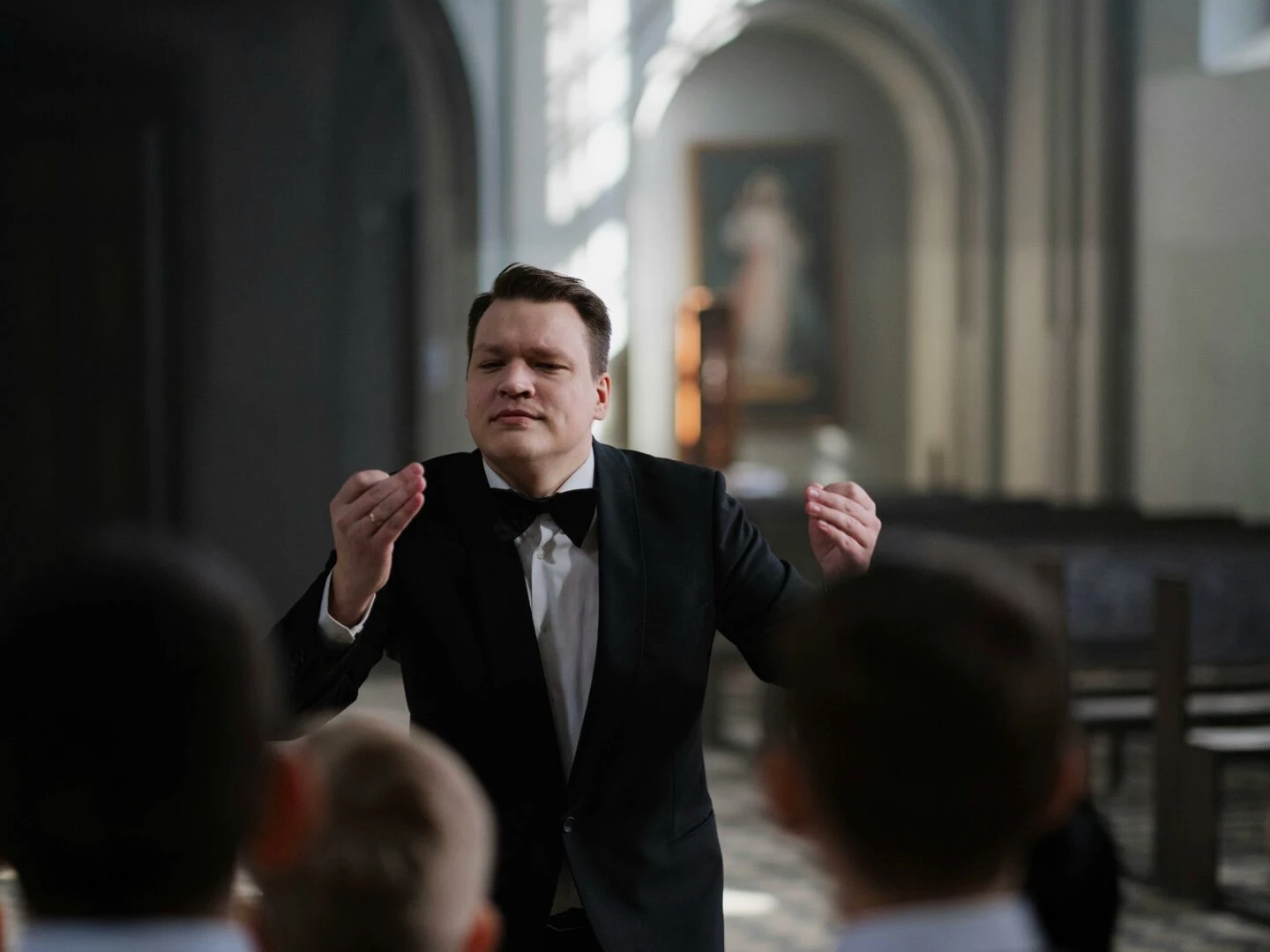 a male conductor leads a boys39 choir rehearsal in a serene church setting