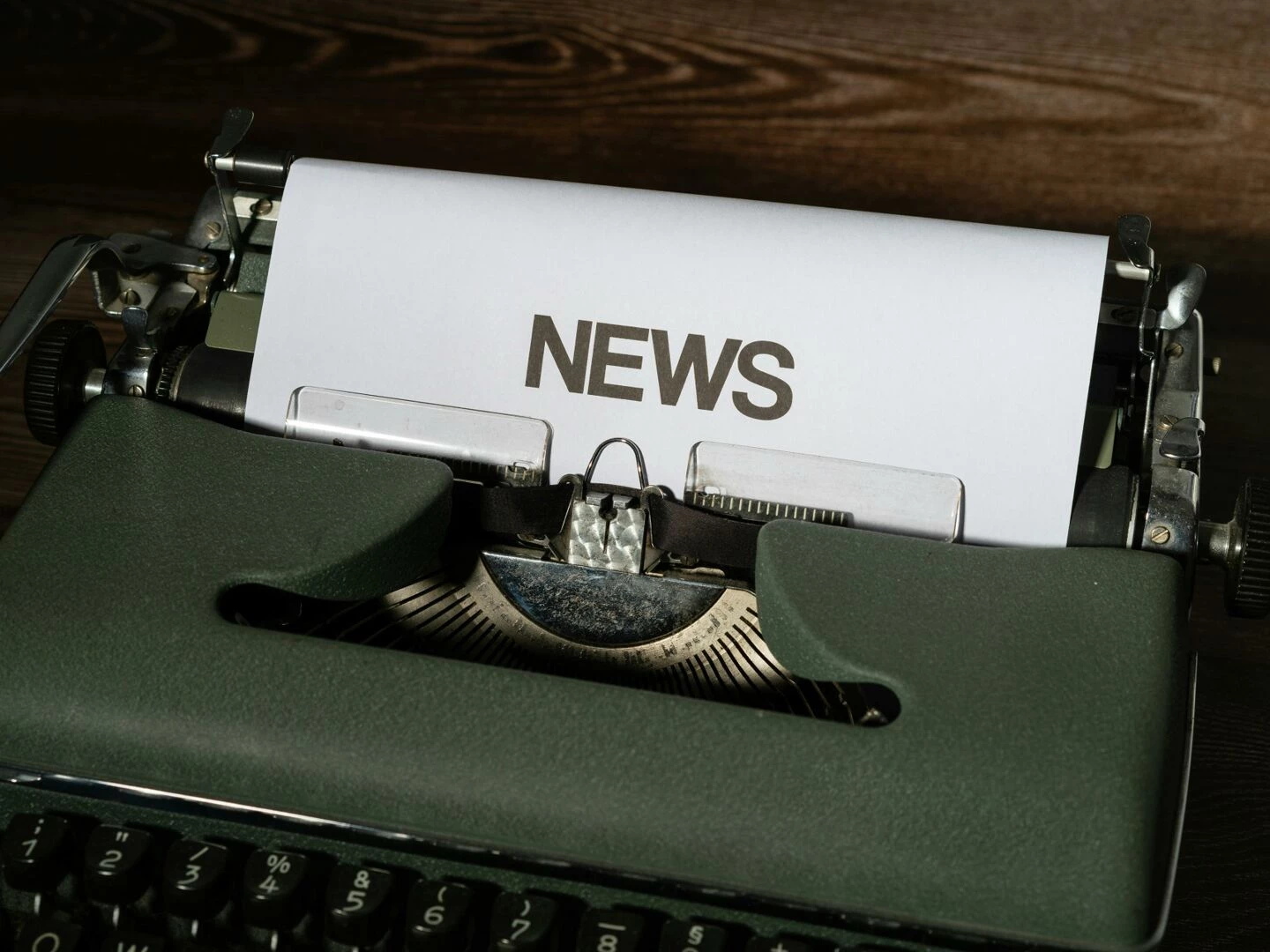a retro typewriter featuring a 39news39 headline typed on white paper against a wooden surface