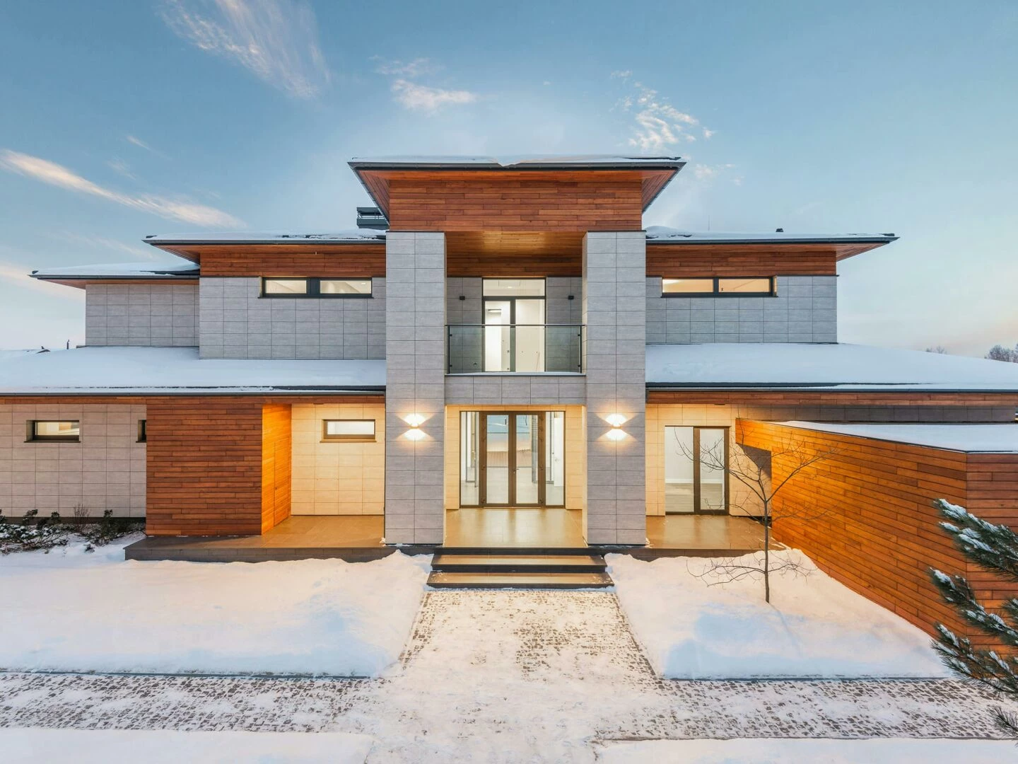 backyard view of new modern luxurious cottage house with stone and wooden facade and illumination in winter countryside
