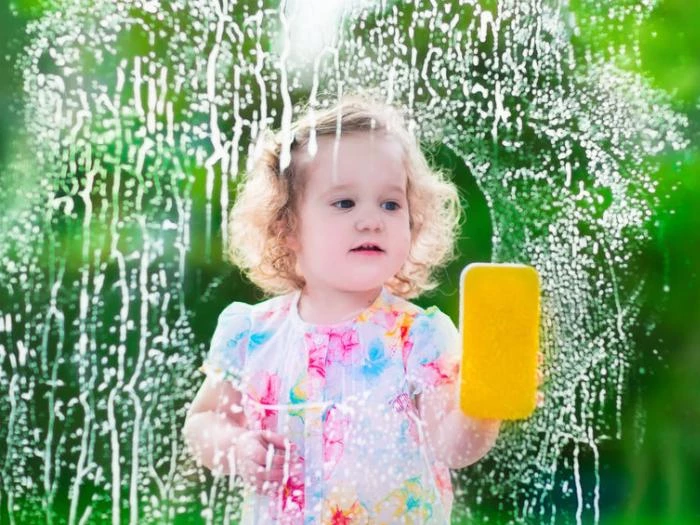 Child cleaning window with sponge