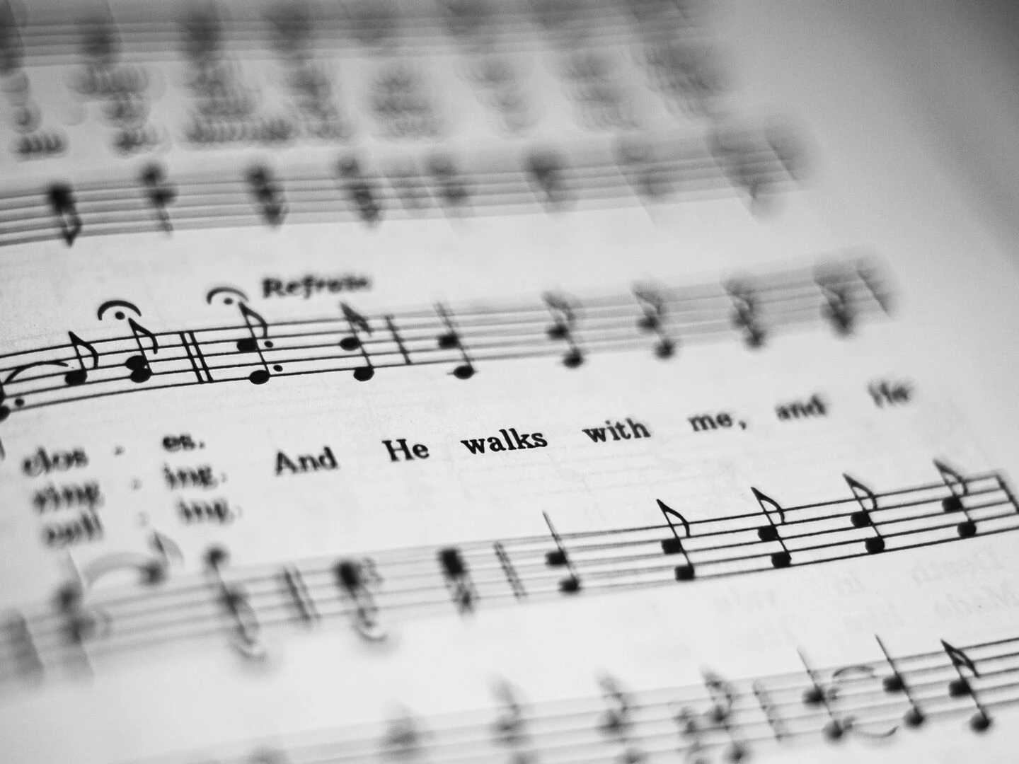 closeup of black and white sheet music featuring musical notes and lyrics in focus