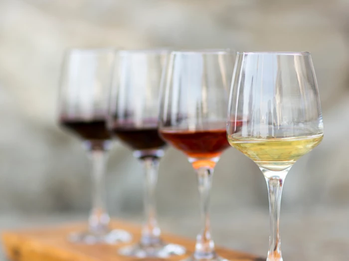 four glasses of wine on a wooden platter