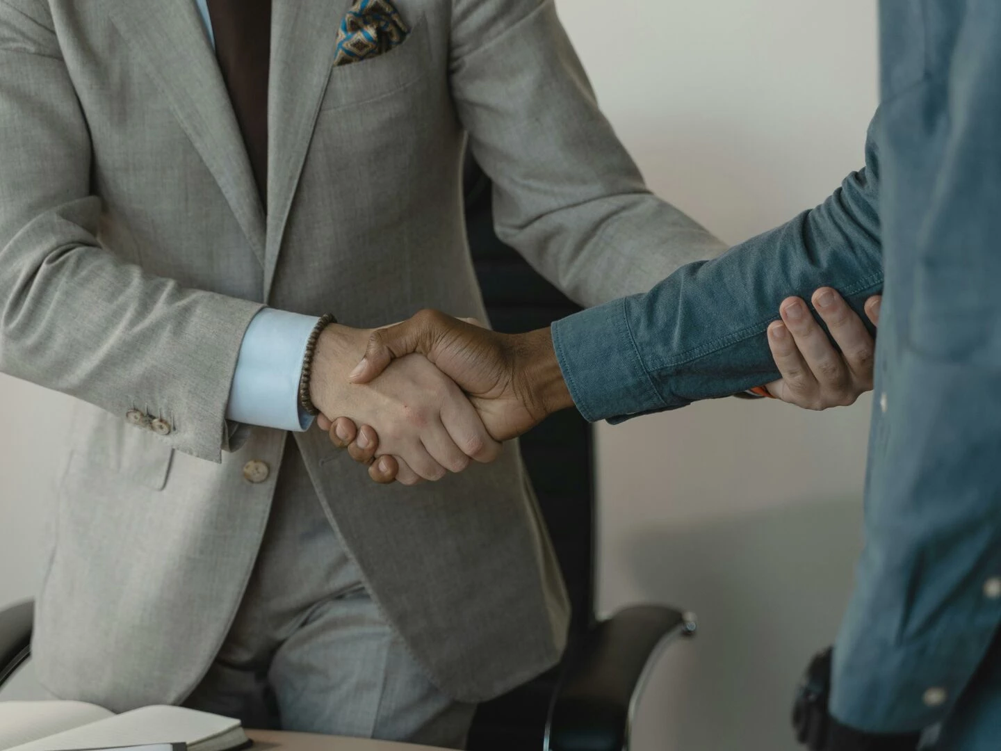 image of a professional handshake between two businessmen in an office setting