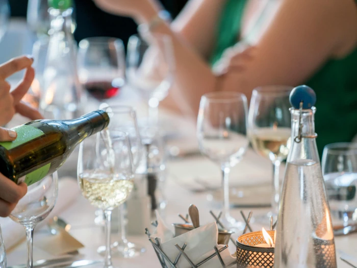 person pouring wine on clear wine glass