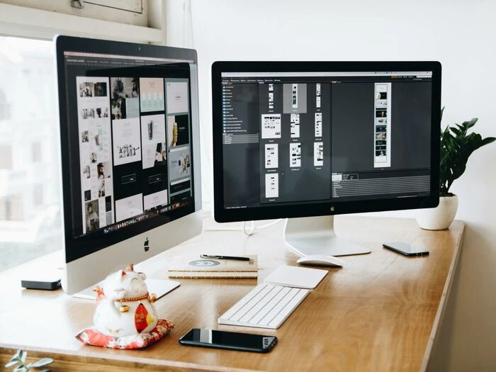 two imac39s with keyboard and phones on desk