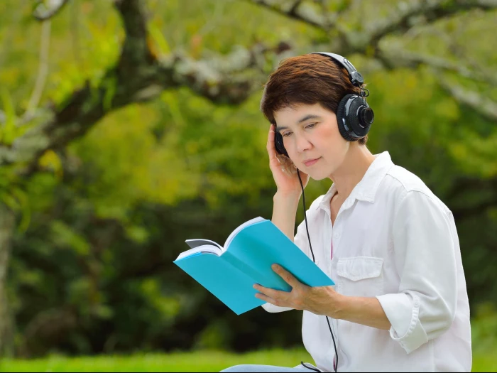woman book listening headphones trees