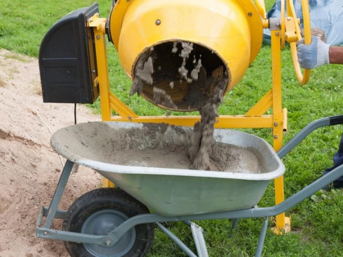 worker fills cement concrete mixer